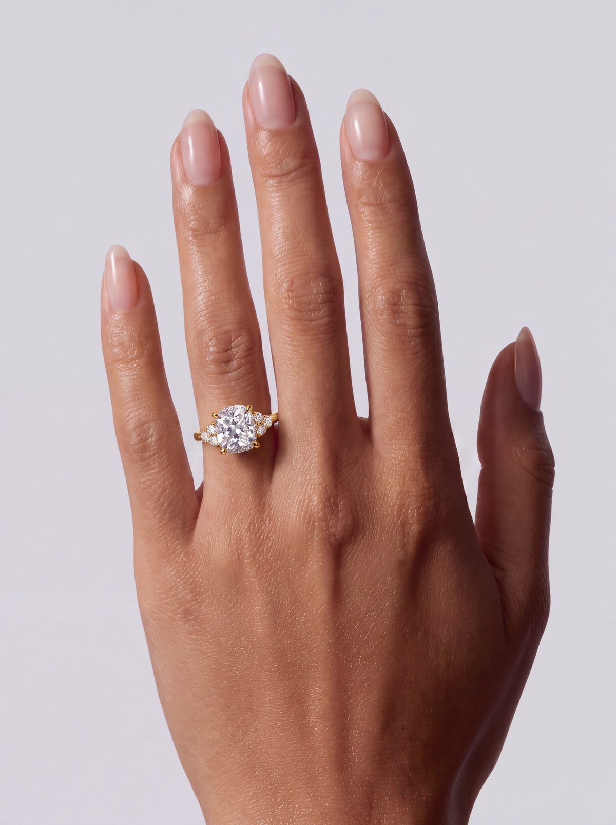 Adeline – Cushion Solitär Verlobungsring mit Seitensteinen in Gelbgold, getragen an der Hand | Élysée Diamonds