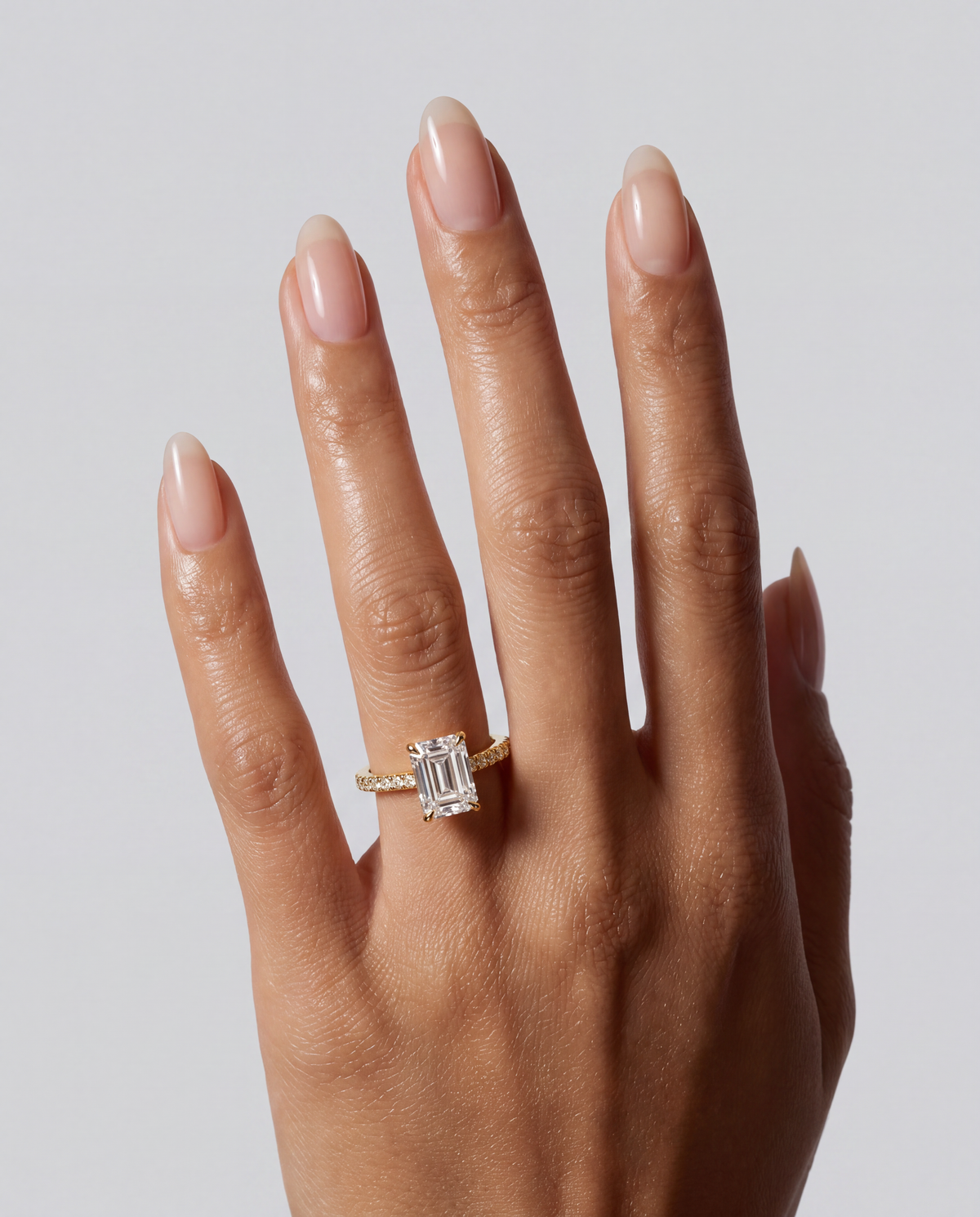 Isola – Emerald Verlobungsring mit Hidden Halo & Pavé in Gelbgold, getragen an der Hand | Élysée Diamonds