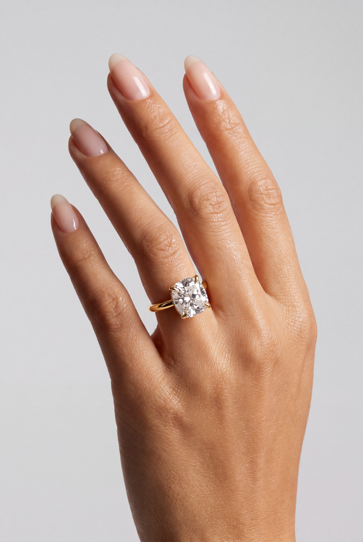 Sorella – Cushion Verlobungsring mit Hidden Halo in Gelbgold, getragen an der Hand | Élysée Diamonds