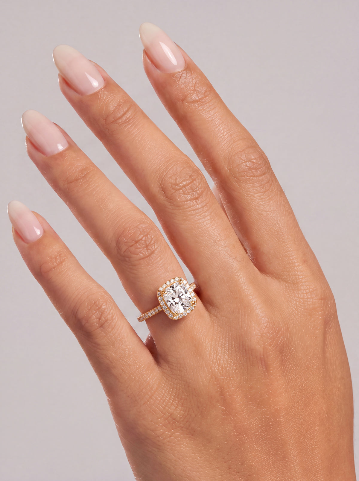 Capucine – Cushion Verlobungsring mit Halo & Pavé in Gelbgold, getragen an der Hand | Élysée Diamonds